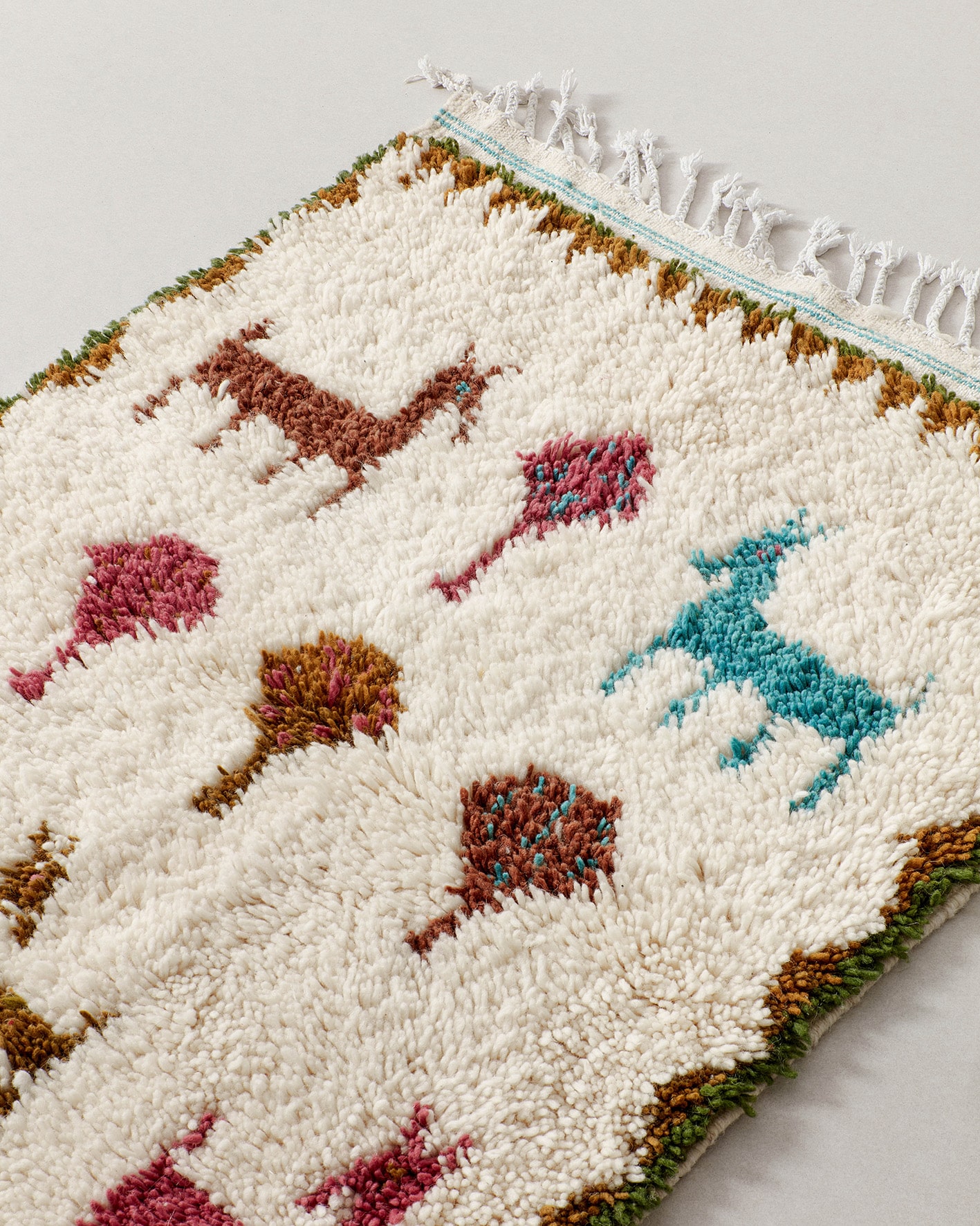 Tiny rug featuring animals in a rust and teal colour palette, close